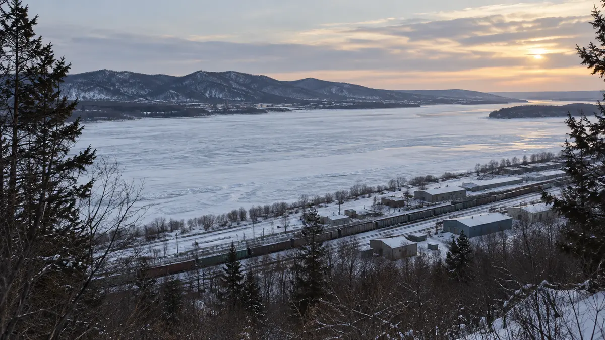 A winter riverside industrial landscape with railway tracks